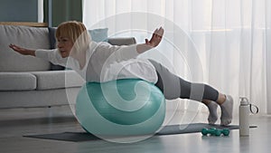 Older Lady Exercising On Swiss Ball Having Workout At Home