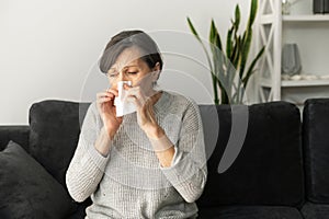 An older lady sneezing at home
