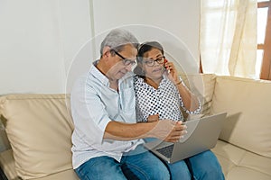 Older Latino web-surfing couple with laptop and cell phone.