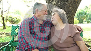 Older lovely couple kissing each other at park in summer. Grandmother and grandfather give kiss each other for love, romance. Seni