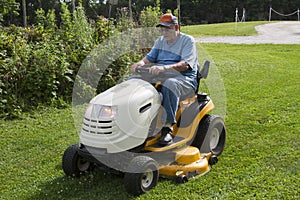 Older Male Mowing Grass With His Riding Mower