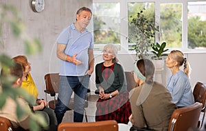 Older male psychologist conducting a group session with mature clients