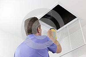 Man Inspecting an Air Duct with a Flashlight photo