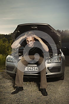 Older man alone on route checking unfunctional engine in late summer light