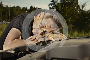 Older man alone on route checking unfunctional engine in late summer light