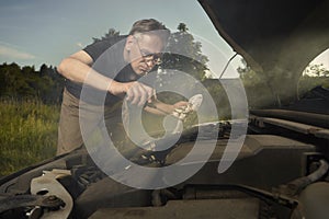 Older man alone on route checking unfunctional engine in late summer light