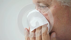 Older man blows his nose