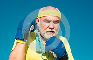 Older man boxing - close up portrait. Handsome elderly man practicing boxing kicks. Senior sport man wearing boxing