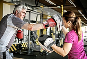 Older man boxing in gym. Senior man with personal trainer.