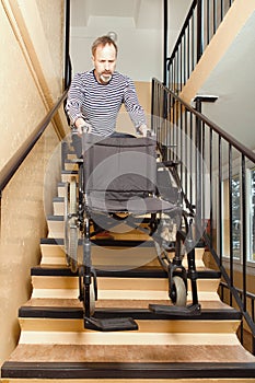 Older man helping with wheel chair to move it down strairs in prefab house