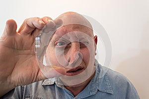 Older man looking through a large lens, distortion, bald, alopecia, chemotherapy, cancer, on white