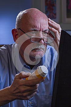 Older man looks confused while refilling prescription online, vertical
