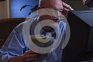 Older man looks worried as he pays bills online, horizontal