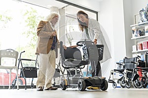 Older man in an orthopedic shop trying out an electric scooter