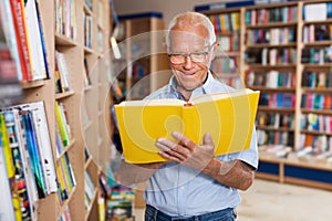 Older man reader browsing inside of books in bookshop