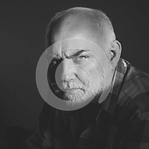 Older man with a serious look. Man with grey beard, frown brows on serious face