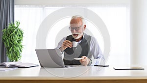 Older man sitting at the desk drinking espresso