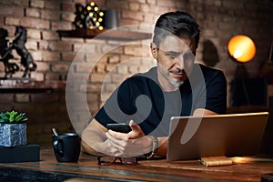 Older man sitting at desk using phone and tablet