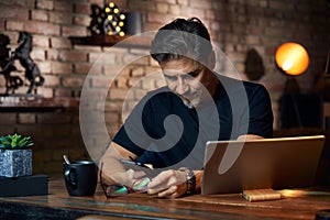 Older man sitting at desk using phone and tablet