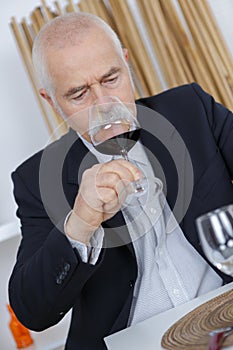 Older man smelling red wine