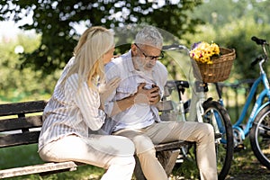 Older man suffering heart attack while sitting on bench in park