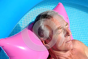 Older man sunbathing on a lilo