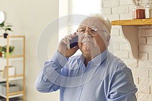 Older man talks on the phone, looks up thoughtfully and listens carefully to the interlocutor. photo