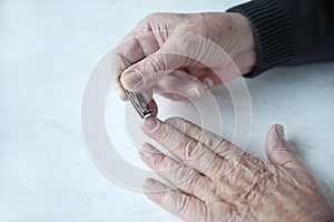 Older man trims fingernails