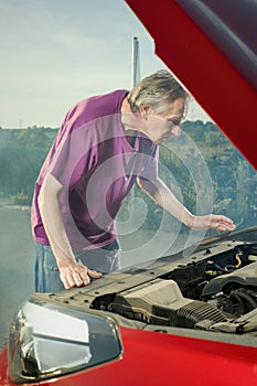 Older man on trip desperate od his car with smoking engine and breakdown