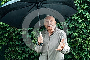 Older man with an umbrella under a stormy sky. An old man with a mustache hides from the rain under an umbrella