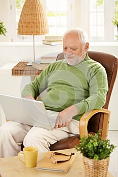 Older man using laptop computer at home
