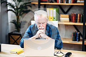 Older man is using laptop for working indoor