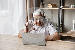 Older man wear headset start videoconference seated at table photo