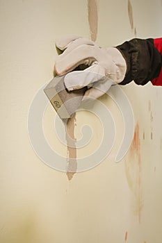 Older worker sanding apartment walls before painting with sanding sponge photo