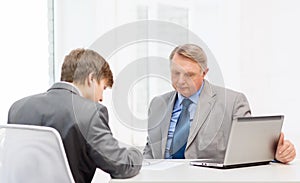 Older man and young man signing papers in office