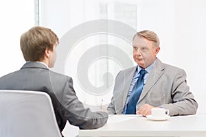 Older man and young man signing papers in office