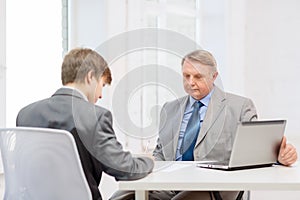 Older man and young man signing papers in office