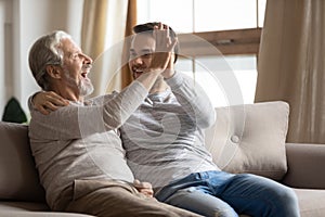 Older mature man giving high five to happy grownup son.