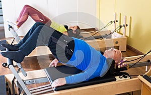 Older man doing exercises of remedial gymnastic on Pilates reformer photo