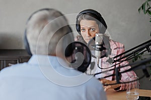 older man and female presenter in a recording studio create a podcast. senior, woman radio presenter or interviewer