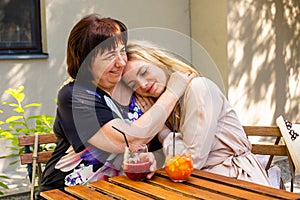 The older mom and daughter are drinking juices in a cafe