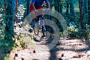 Older overweight man rides a mountain bike through the woods using extreme effort