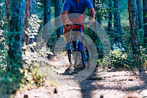 Older overweight man rides a mountain bike through the woods using extreme effort