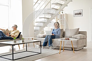 Older senior family couple spending time at home in modern living room.