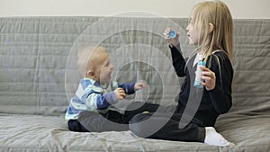 The older sister gives a lot of soap bubbles to her younger brother.
