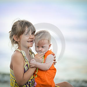 Older sister holds a beautiful girl with Down syndrome