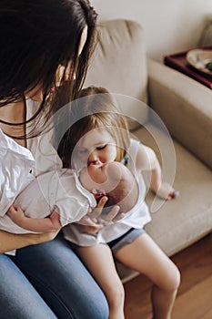 Older sister kissing newborn bother holding by mom. Siblings and mother