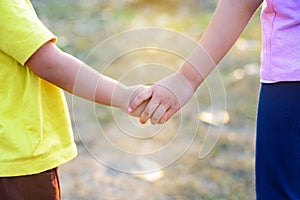 Older sister`s hand holding her brother`s hand together