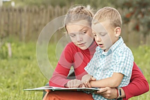 Older sister teaches little brother to read primer. Happy children are studying book. Mother reading with son. Toddler Reading ABC