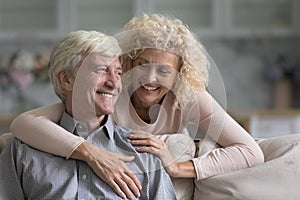 Older smiling wife hugs her beloved cheerful husband